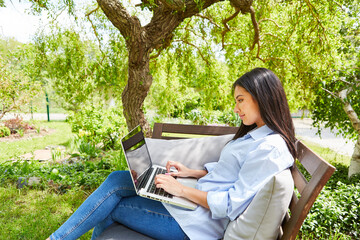 Frau als Influencer oder Freelancer am Laptop im Garten