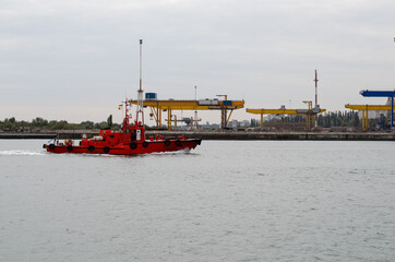 Marine ship. Sea tug. A small ship is sailing to the port. Sea lighthouse on the shore.