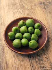 Mini kiwis (Actinidia arguta) on an stoneware plate on a rustic kitchen table, healthy food