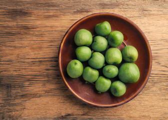Mini kiwis (Actinidia arguta) on an stoneware plate on a rustic kitchen table, healthy food
