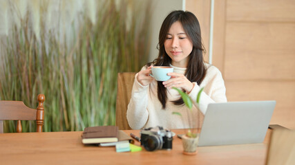 Young woman sitting in a beautiful coffee shop, drinking hot coffee in the morning