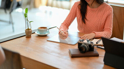 Young female freelance blogger in comfy sweater using stylus pen on tablet computer