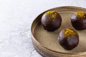 Truffles with turmeric in dark chocolate on a plate. Sugar, gluten and lactose free, vegan.