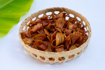 Banana slice chips in bamboo basket on white background.