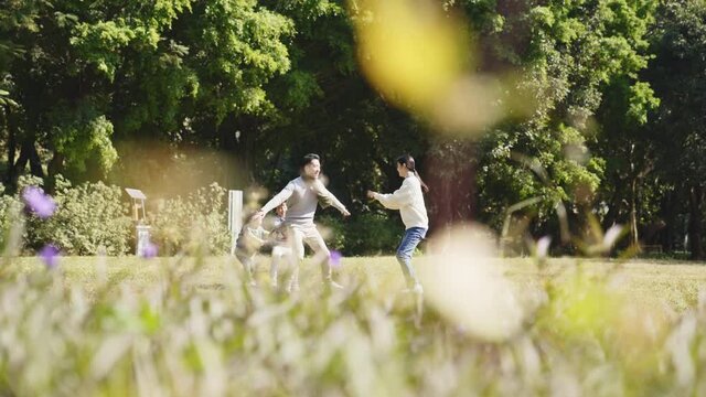 happy asian family with two children having fun outdoors in park