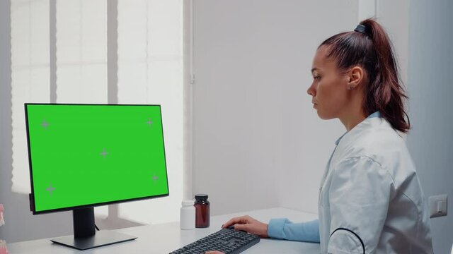 Dentist working with horizontal green screen on computer for teethcare at dental office. Woman using keyboard and monitor with chroma key for mockup template and isolated background