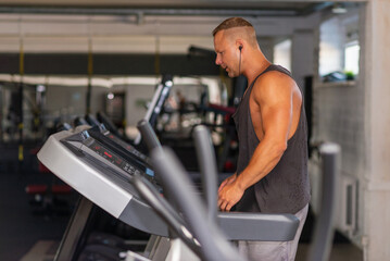 Young man in sportswear running on treadmill at gym.Handsome sport gym man running on the treadmill.Indoors shot.