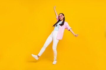 Full size photo of young happy dark skin funky woman smile dance wear sunglass isolated on yellow color background