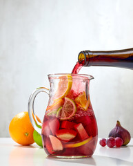 red wine pouring into jug of cutted fruits