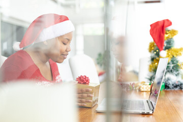 Happy african american plus size woman in santa hat making christmas video call on laptop