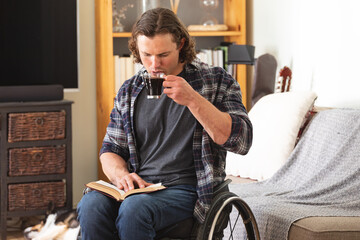 Caucasian disabled man sitting on wheelchair drinking coffee and reading a book at home