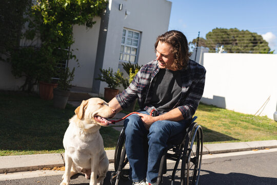 Caucasian disabled man with dog sitting on wheelchair on the road