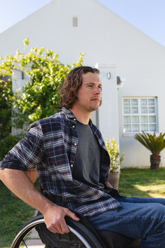 Caucasian disabled young man sitting on wheelchair smiling in the garden