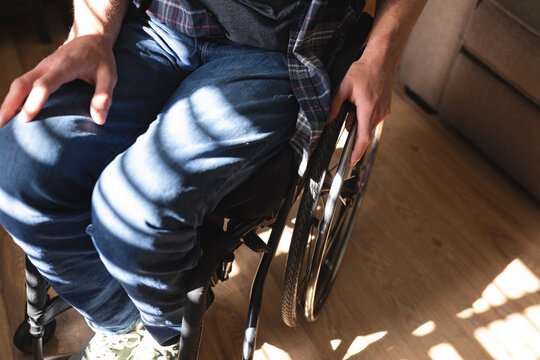 Mid section of caucasian disabled man sitting on wheelchair at home