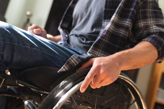Mid section of caucasian disabled man sitting on wheelchair at home