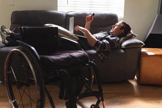 Caucasian disabled man using laptop while lying on the couch at home