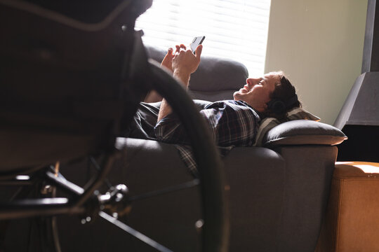 Caucasian disabled man using smartphone while lying on the couch at home