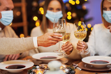 Friends celebrating christmas party wearing mask.