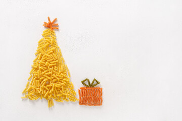 Alternative Christmas tree of dry pasta coloful fusilli with gift on white background. Merry Xmas...