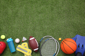 Different sport equipment on green grass, flat lay. Space for text © New Africa