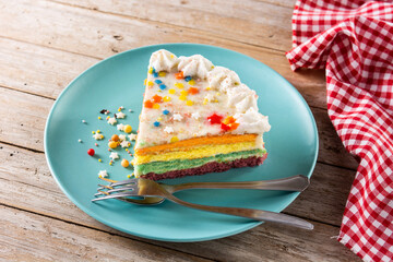 Rainbow layer cake piece on wooden table