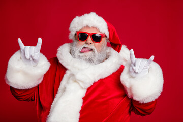 Photo of funny crazy rude careless old man show horns protrude tongue wear santa hat costume isolated red color background