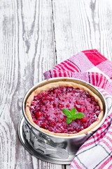 Freshly baked red currant pie in baking form on white wooden table