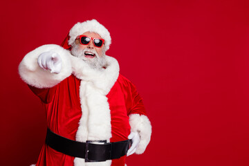 Portrait of attractive cheerful confident Santa pointing at you copy space select isolated over bright red color background