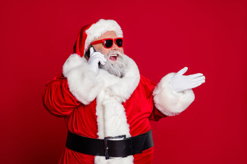 Fototapeta na wymiar Portrait of attractive bearded cheery Santa calling using roaming talking contact isolated over bright red color background