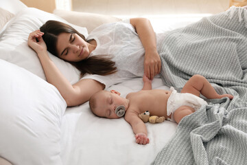 Mother with her cute baby sleeping in bed