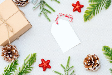 Christmas blank greeting card in frame of fir branches, decorations, gift box and cones over white background.mockup. flat lay. top view.