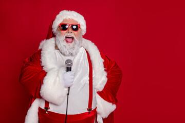 Photo of funny carefree old man hold mic sing x-mas carol wear santa hat costume isolated red color...