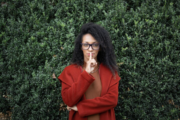 Pensive stylish black woman doing silence gesture with her finger on her lips. Make a decision...