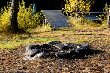 A beautiful fireplace by the forest lake with a wet footbridge and yellow birches