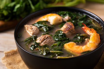 Beef, okra stew and spinach soup in bowl on wooden table	
