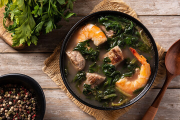 Beef, okra stew and spinach soup in bowl on wooden table	
