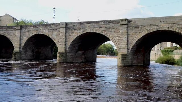 A beautiful old bridge going over the River Wharfe in the British town of Wetherby in Leeds, West Yorkshire in the UK, showing the stone brick bridge going in to the village on a hot sunny summers day