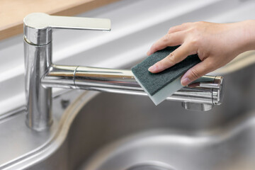 台所の蛇口を掃除する女性の手のイメージ