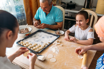 family traditions, Family, mom and daughter, grandmother and grandfather, together at the table make dumplings