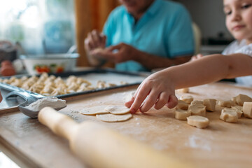 family traditions, grandfather and granddaughter make dumplings together at the table, grandfather helps granddaughter