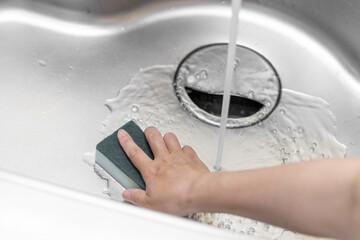 台所の流し台を掃除する女性の手のイメージ