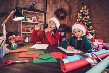 Portrait of two attractive cheerful curious dreamy siblings writing letters creating craft at brick loft home indoors