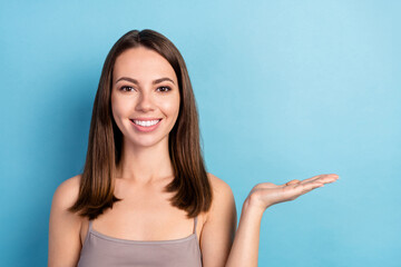 Fototapeta premium Portrait of attractive cheerful girl holding on palm copy empty space ad decision isolated over bright blue color background