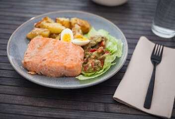 baked salmon fillet with fried potato wedges, homemade guacamole and quail eggs halves