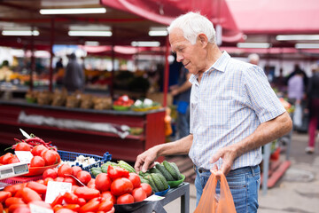 retired european man buying tomatoes in market