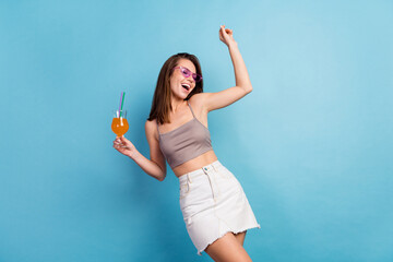 Photo of joyful young positive woman hold hands cocktail dance weekend vacation isolated on blue...