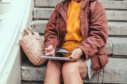 Businesswoman hand working uses modern tablet device while sitting on the street