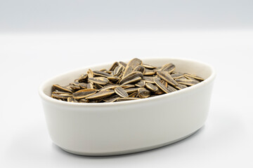 Sunflower seeds on a white background. Ceramic plate filled with sunflower seeds