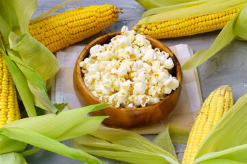 Tasty traditional popcorn and corn cobs on grey background