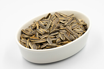 Sunflower seeds on a white background. Ceramic plate filled with sunflower seeds